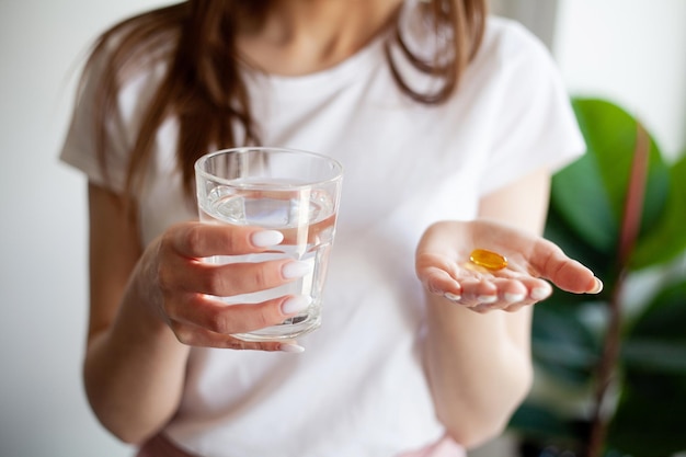 Linda mulher segurando a cápsula com uma fonte de óleo de peixe de ácidos graxos omega3