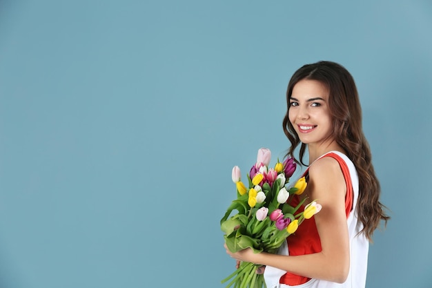 Linda mulher segurando o buquê de tulipas na cor de fundo