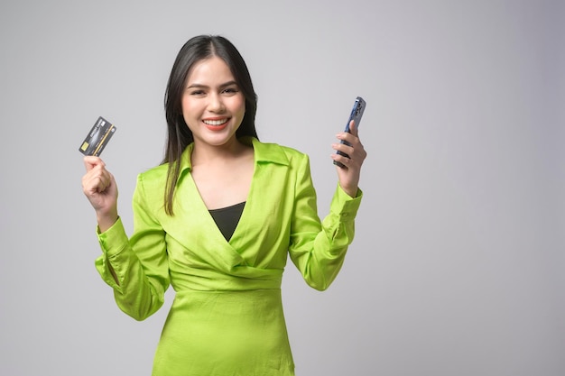 Linda mulher segurando o cartão de crédito e smartphone sobre fundo branco