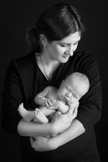 Linda mulher segurando um bebê recém-nascido em seus braços Fundo preto
