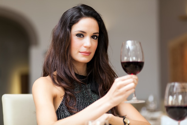 Foto linda mulher segurando um copo de vinho tinto