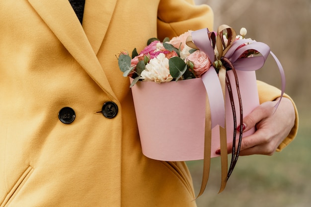 Linda mulher segurando uma caixa rosa com flores. Presente para o Dia da Mulher.