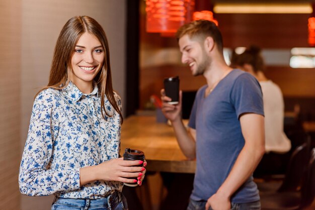 Linda mulher segurando uma xícara de café e um homem tirando uma foto dela