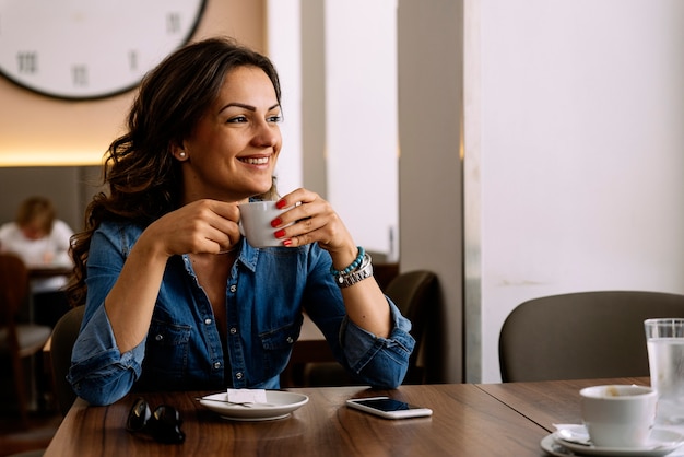 Linda mulher segurando uma xícara de café na cafeteria.