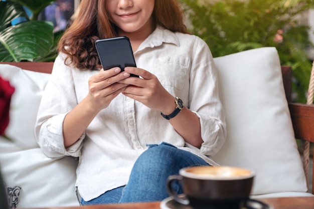 linda mulher segurando, usando e olhando para um telefone inteligente no café