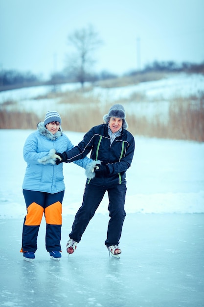 Linda mulher sênior e homem na patinação no gelo de natureza ensolarada de inverno.