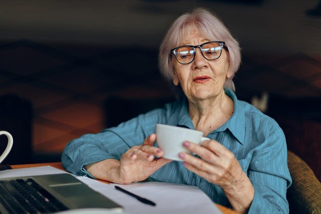 Linda mulher sênior madura trabalhando em frente ao monitor de laptop sentado estilo de vida inalterado