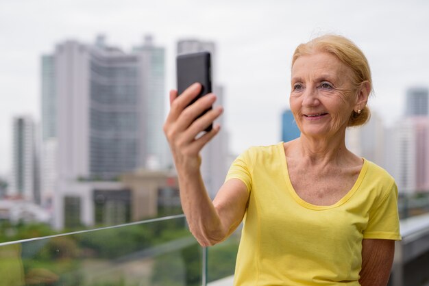 Linda mulher sênior usando telefone celular na cidade