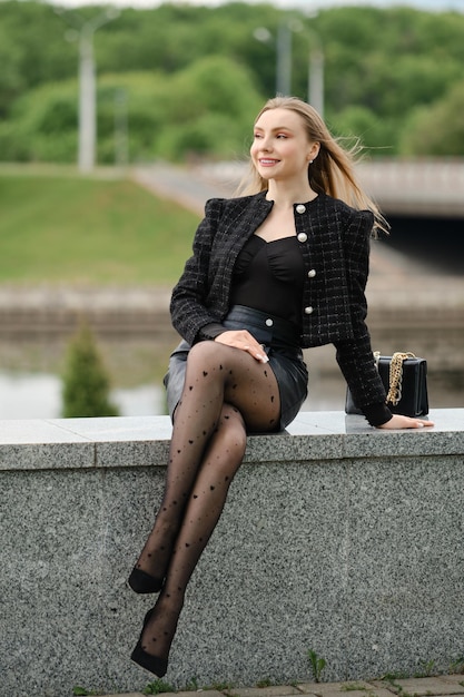 Linda mulher sentada na margem do rio no parque da cidade perto de seu escritório