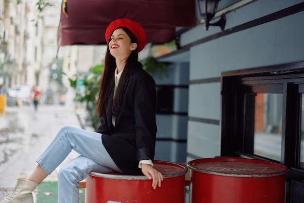 Linda mulher sorri com dentes sentada do lado de fora de um café e bar em uma rua da cidade elegante vestido chique parece férias e viagens