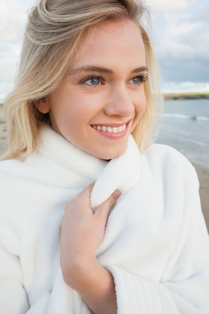 Linda mulher sorridente com elegante jaqueta branca na praia