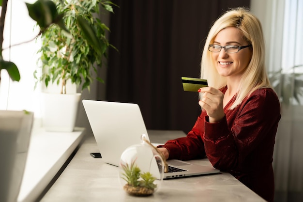 Linda mulher sorridente com laptop e cartão de crédito, comprando online