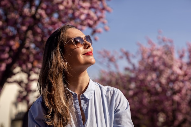 Linda mulher sorridente no fundo das flores de cerejeira rosa lilás