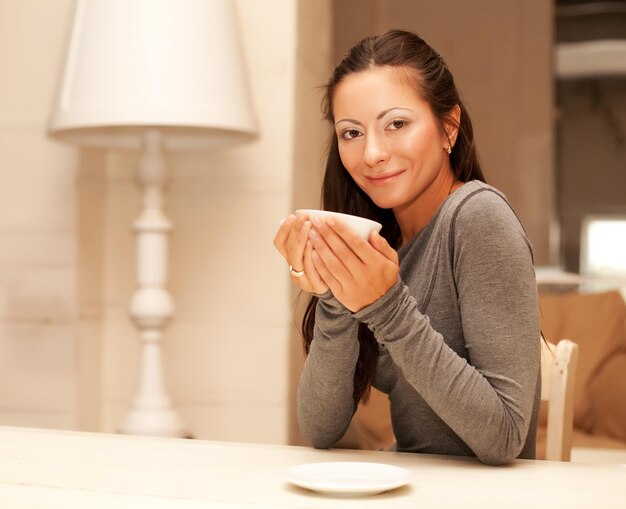 Foto linda mulher sorridente tomando café. casa.