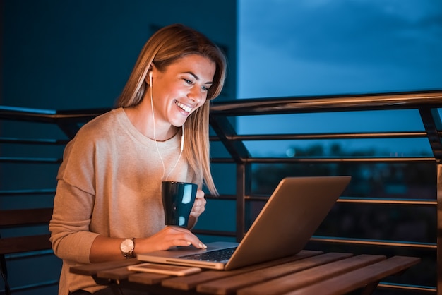 Linda mulher sorridente usando laptop à noite.