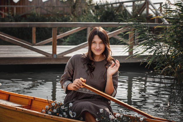 Linda mulher sozinha em um barco de madeira flutuando no lago - privacidade com a natureza