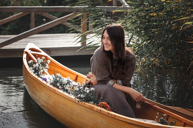 Linda mulher sozinha em um barco de madeira flutuando no lago - privacidade com a natureza