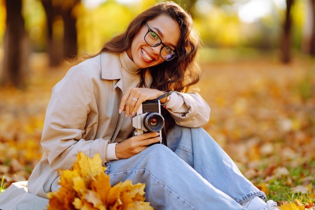 Linda mulher tirando fotos na floresta de outono Mulher aproveitando o clima de outono Conceito de estilo de vida