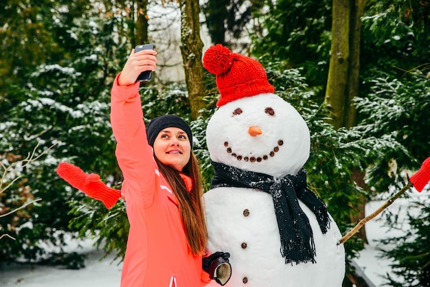 Linda mulher tomando selfie com boneco de neve