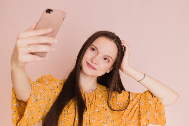 Linda mulher tomando selfie no fundo rosa