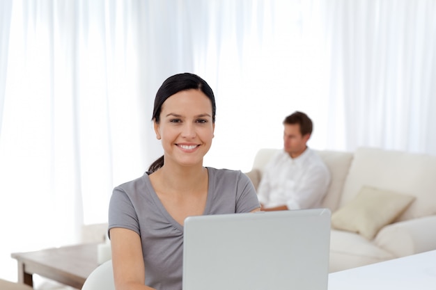 Linda mulher trabalhando no laptop enquanto o marido relaxa