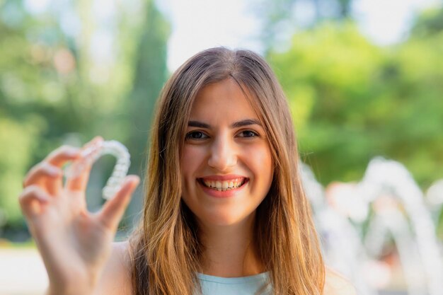 Linda mulher turca sorridente está segurando uma braçadeira invisalign