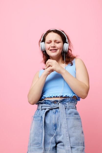 Linda mulher usando fones de ouvido distração moda dança fundo rosa inalterado