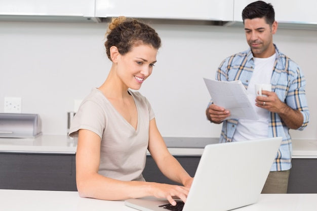 Linda mulher usando o laptop enquanto o parceiro lê o jornal