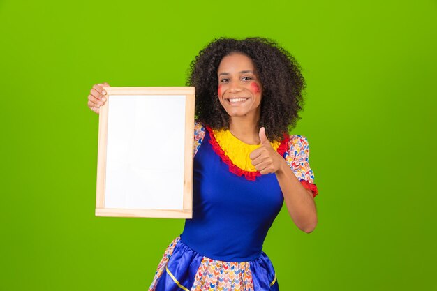 Linda mulher vestida com roupa de festa junina segurando uma placa em branco com espaço de cópia