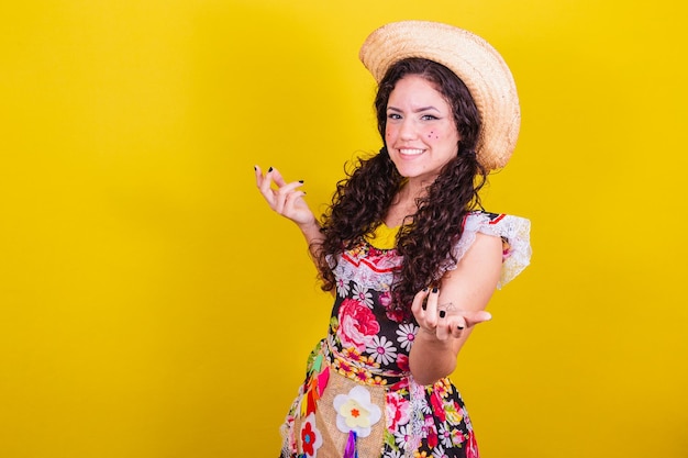 Linda mulher vestida com roupas típicas para uma Festa Junina convidando com as mãos