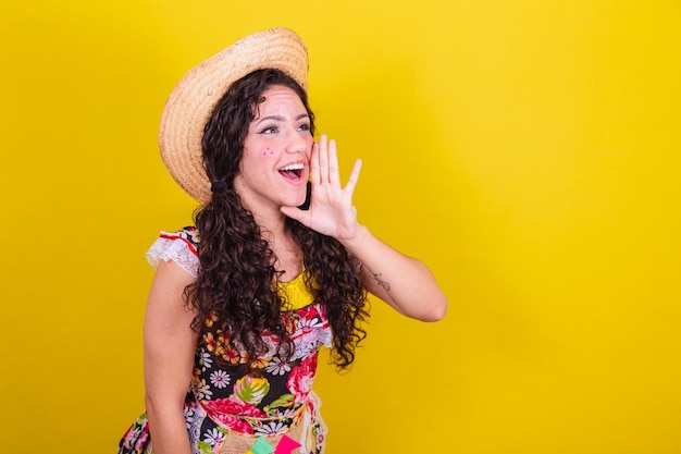 Linda mulher vestida com roupas típicas para uma Festa Junina gritando chamando dizendo desconto de promoção alto