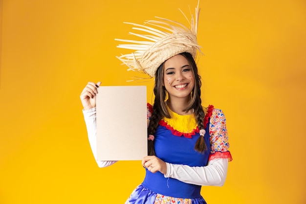 Linda mulher vestida com roupas típicas para uma Festa Junina segurando placa para texto ou anúncio de anúncio