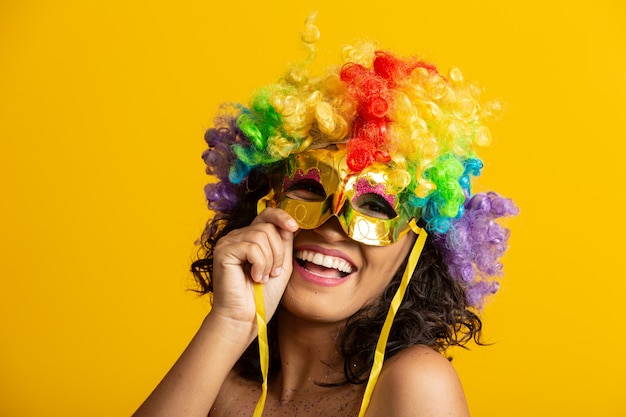 Foto linda mulher vestida para a noite de carnaval. mulher sorridente pronta para curtir o carnaval com uma peruca e máscara coloridas