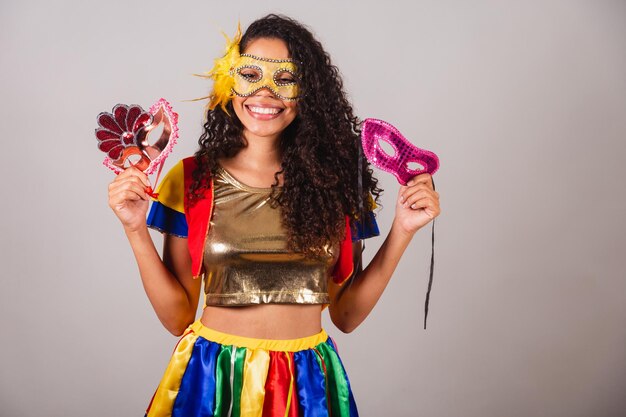 Foto linda negra brasileira com roupas de frevo carnaval vestindo uma máscara segurando máscaras de carnaval convidando as pessoas para a festa