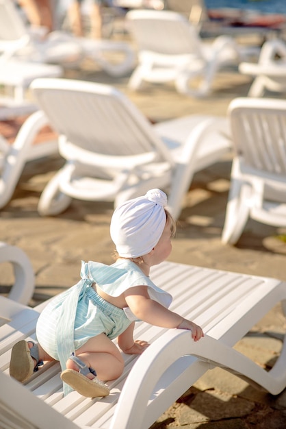 Linda niña de 1 año en la playa en el resort en verano con un traje de moda