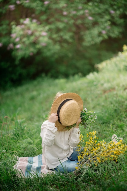 Linda niña de 4 años en un picnic en un bosque floreciente en primavera