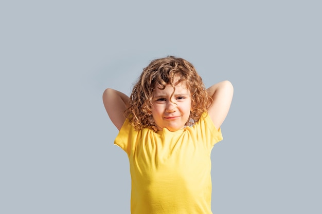 Linda niña de 5 años con camiseta amarilla girando la cabeza en gris