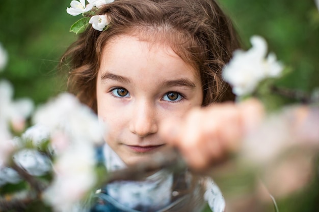 Una linda niña de 5 años en un floreciente huerto de manzanas blancas en primavera Huerto de primavera alergia a la floración fragancia de primavera ternura cuidado de la naturaleza Retrato
