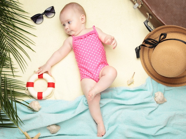 Linda niña con accesorios de playa en luz. Vacaciones en el mar con bebe