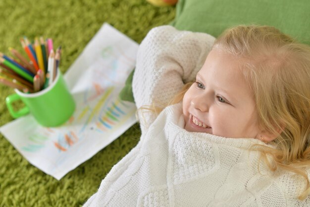 Linda niña acostada en la alfombra verde