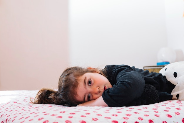 Foto linda niña acostada en la cama