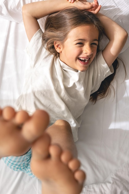 Una linda niña se acuesta en la cama por la mañana y sonríe.