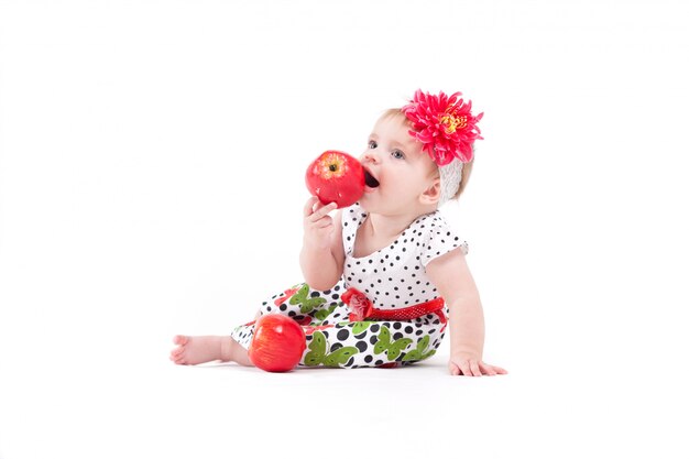 Linda niña alegre en vestido y abrigo comer manzana