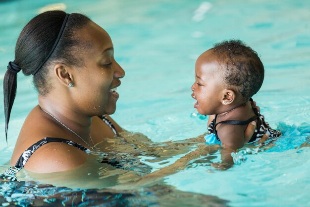 Linda niña aprendiendo a nadar en la piscina cubierta.