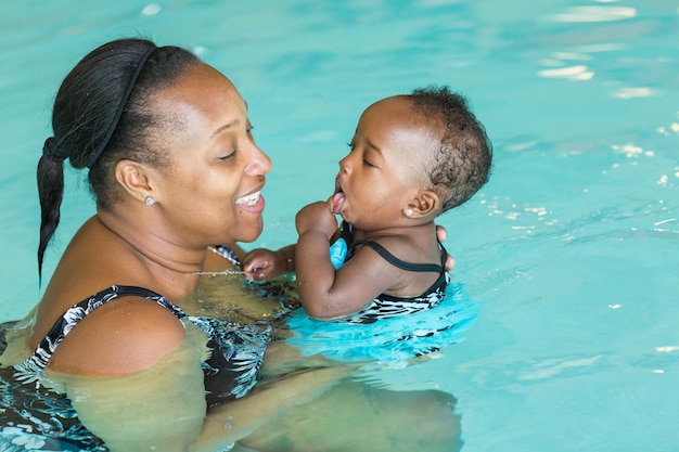 Linda niña aprendiendo a nadar en la piscina cubierta.