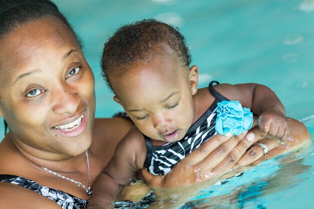 Linda niña aprendiendo a nadar en la piscina cubierta.