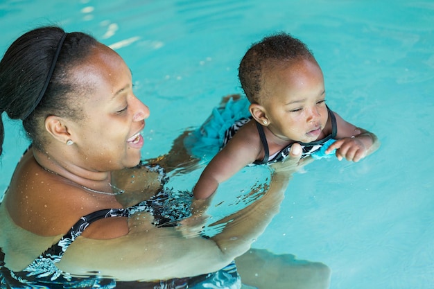 Linda niña aprendiendo a nadar en la piscina cubierta.