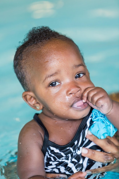 Linda niña aprendiendo a nadar en la piscina cubierta.