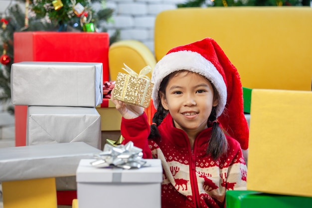 Linda niña asiática con cajas de regalo y decoración para celebrar el festival de Navidad