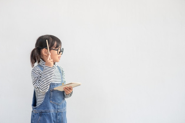 Linda niña asiática con gafas y pensando